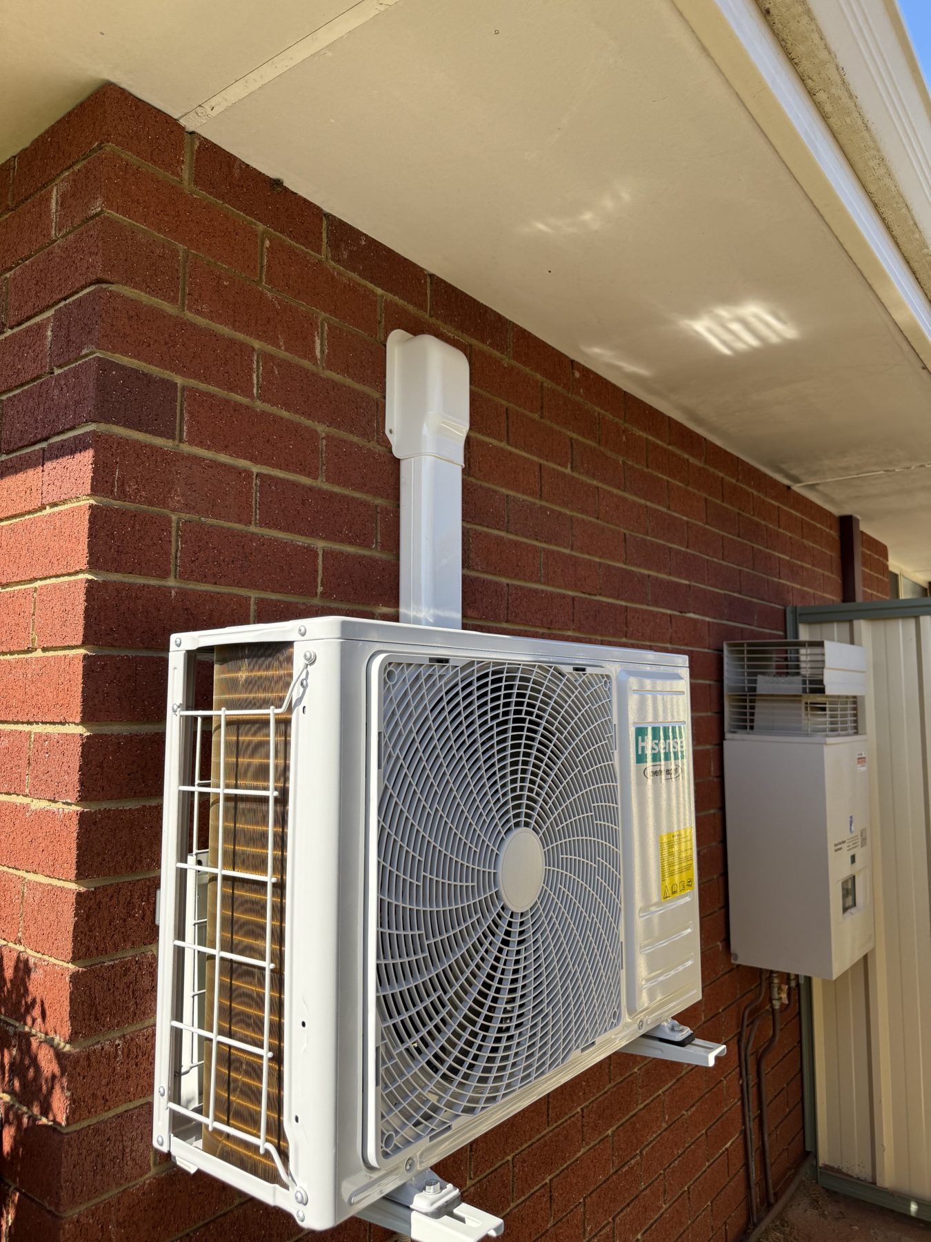 Split system condenser installed under an eave with a capped conduit run